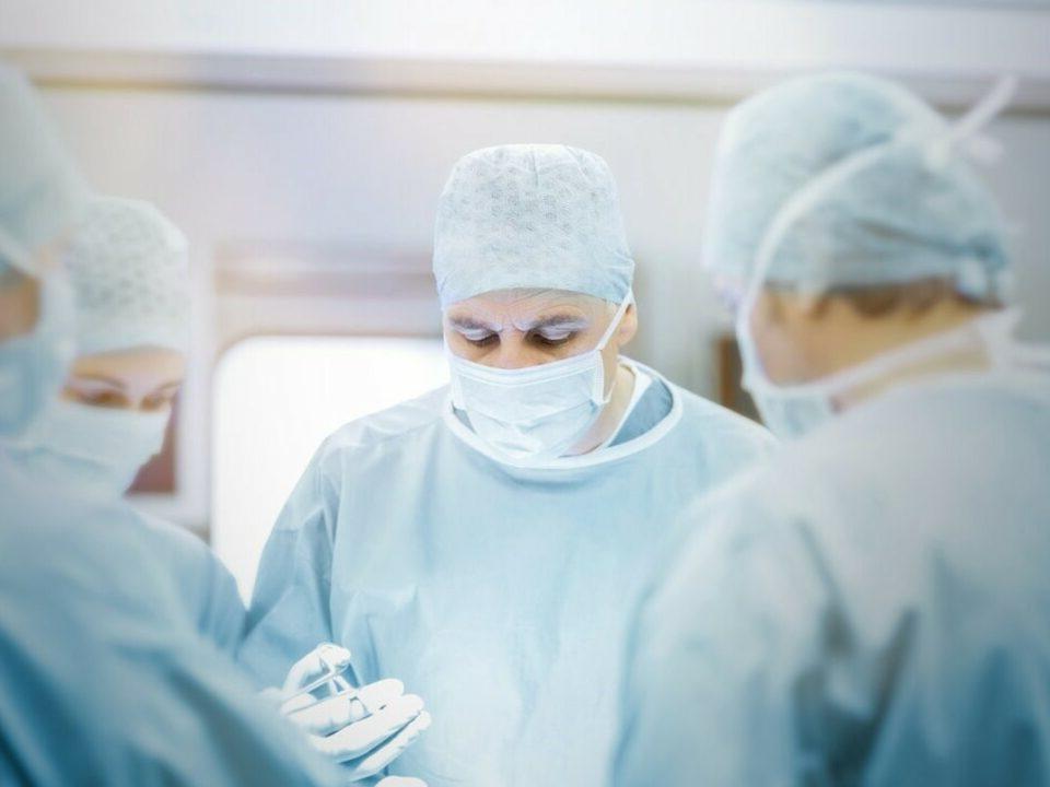 doctors in gown and face masks performing surgery